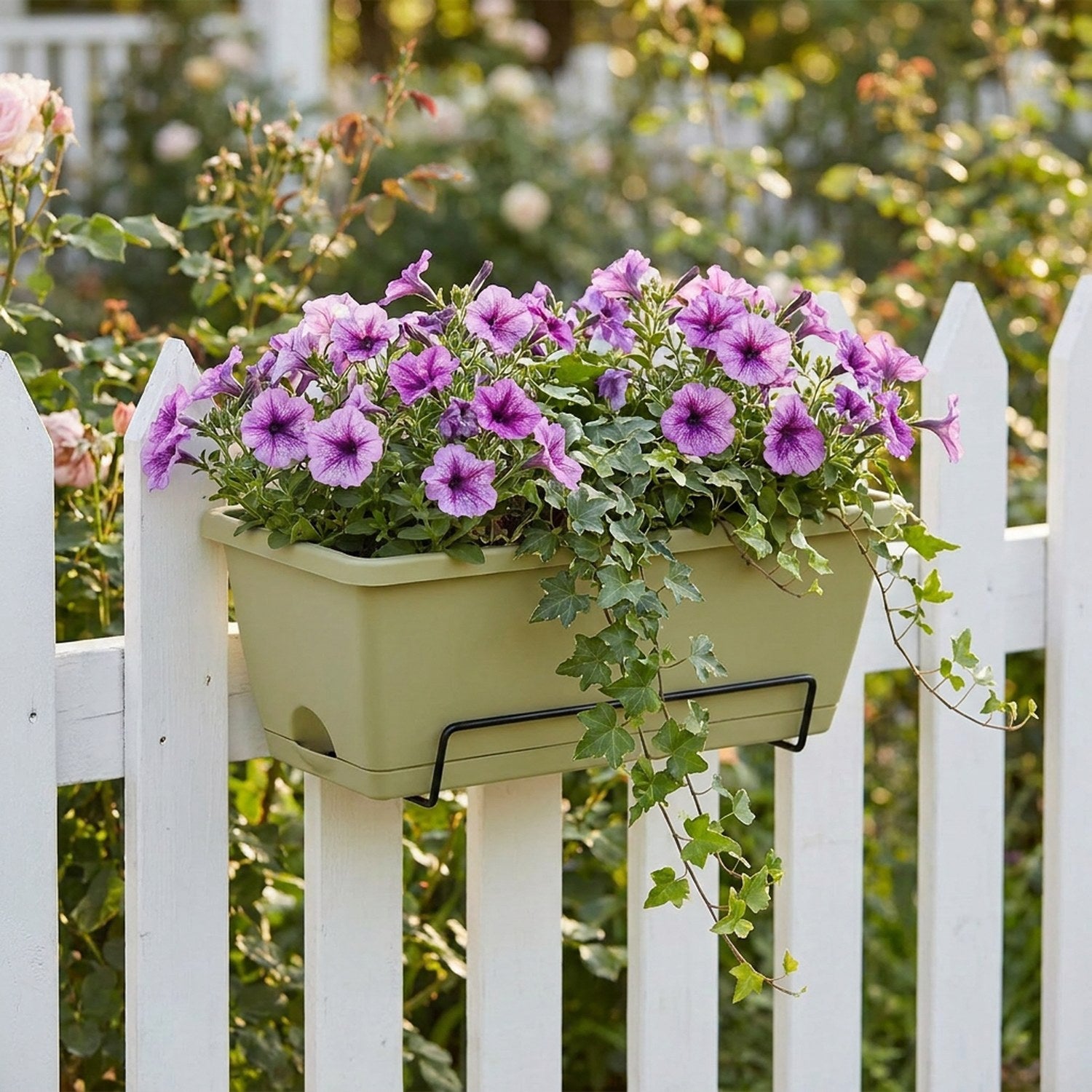 Jardinière de balcon verte avec pétunias sur clôture blanche dans jardin fleuri