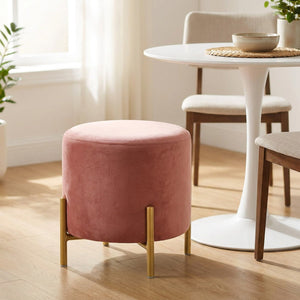 Pouf rond en velours rose utilisé comme siège d'appoint près d'une table