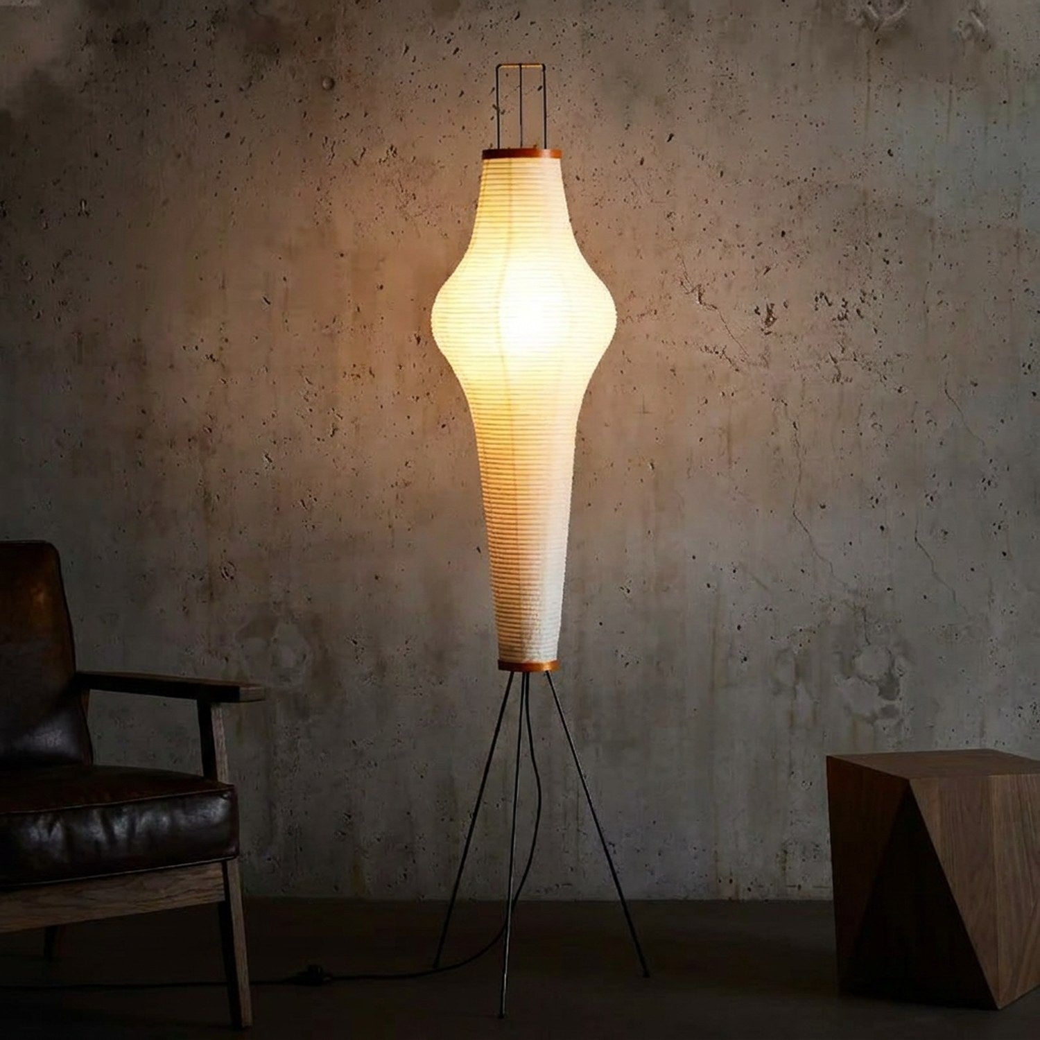 Lampadaire papier de riz allumé contre un mur béton ambiance dramatique