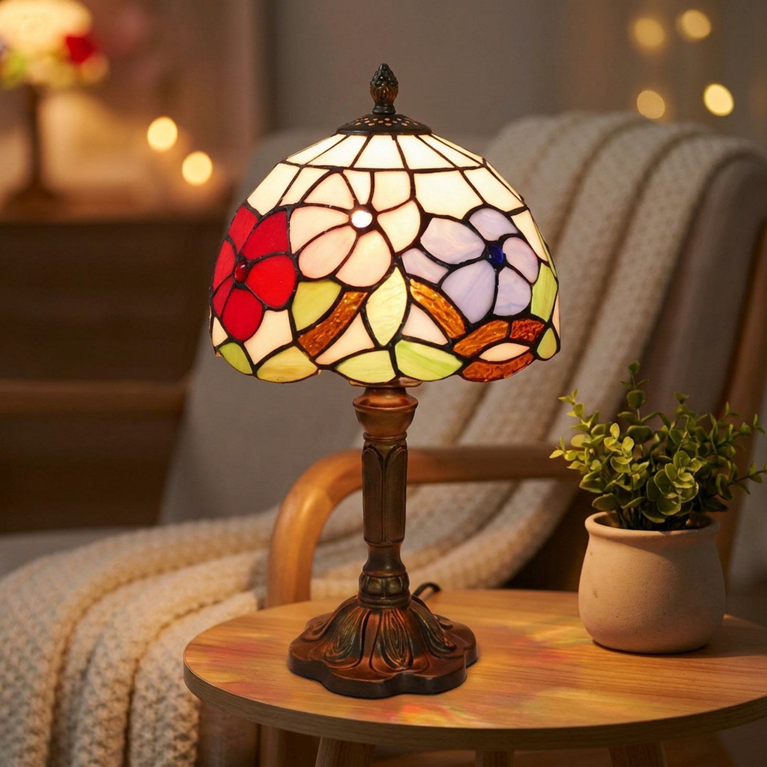 Lampe style Tiffany allumée près d'un fauteuil cocooning avec plaid et plante verte
