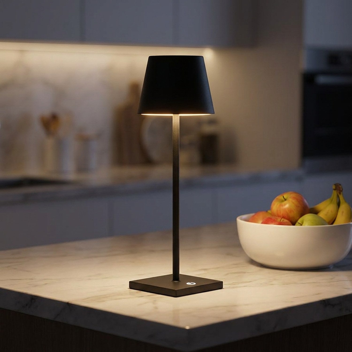 Lampe LED tactile noire allumée sur un plan de travail en marbre