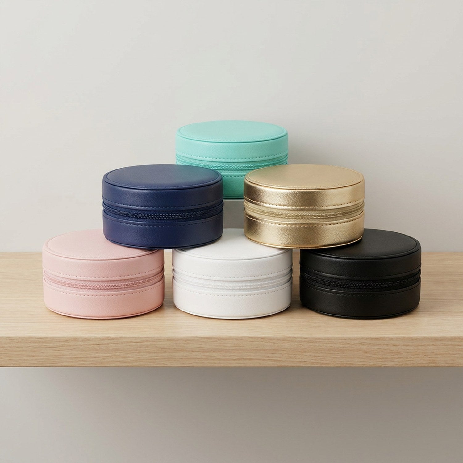 Les 6 coloris du coffret à bijoux de voyage alignés sur une étagère en bois