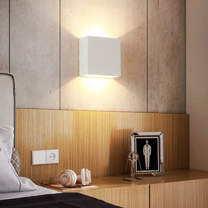 Applique murale LED blanche au dessus d'une table de chevet en bois dans une chambre chaleureuse