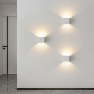 Appliques murales LED blanches alignées dans un couloir moderne avec diffusion lumineuse en losange