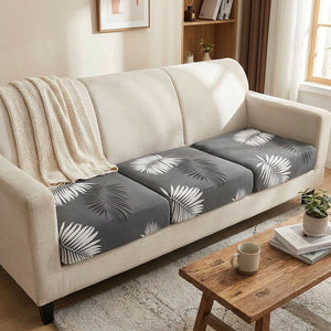 Canapé trois places habillé de housses de coussin grises à motif feuillage dans un salon cosy