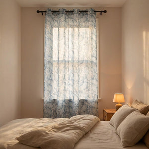 Chambre cocooning avec rideau voilage bleu à feuillage tropical devant la fenêtre
