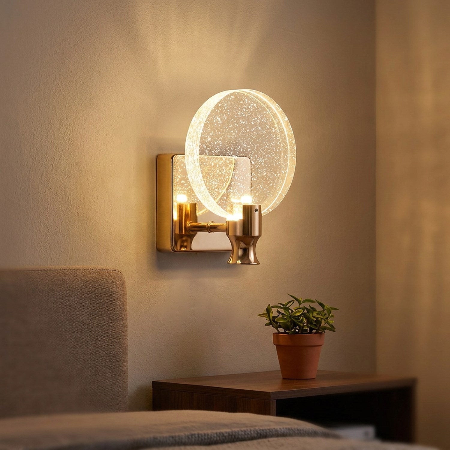 Applique murale dorée au-dessus d'une table de chevet en bois avec une plante
