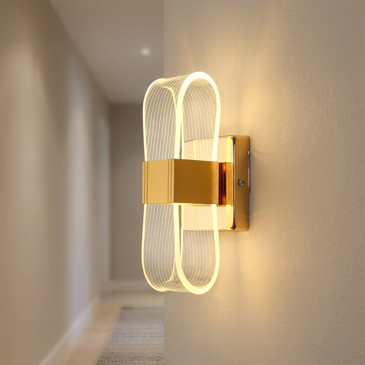 Applique murale dorée dans un couloir épuré diffusant une lumière chaude sur le mur