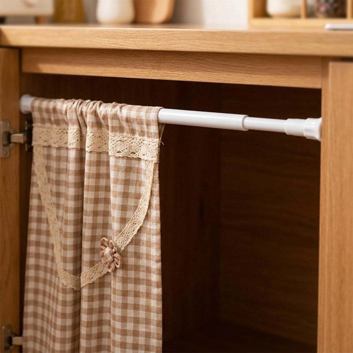 Tringle télescopique installée sous un meuble de cuisine avec rideau à carreaux