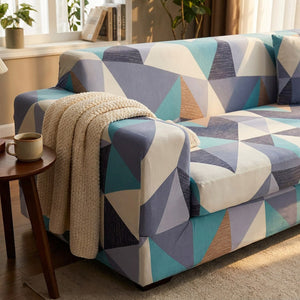 Détail de la housse de canapé élastique motif géométrique bleu sur un accoudoir avec un plaid