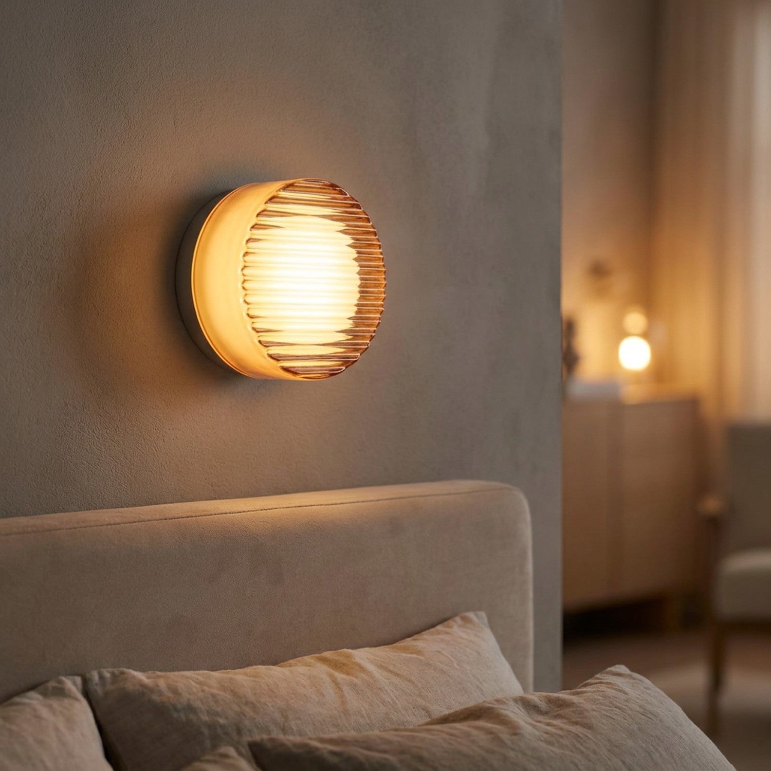 Applique murale LED orange côtelée allumée au dessus d'une tête de lit dans une chambre cosy