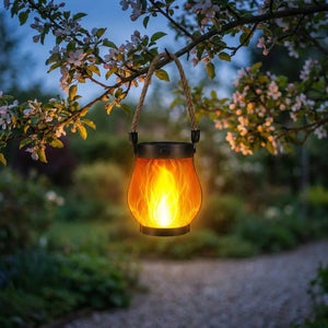 Lanterne solaire à effet flamme suspendue à une branche d'arbre en fleurs au crépuscule