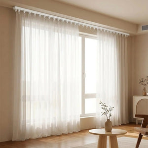 Rail de rideau discret au plafond avec un long voilage blanc dans un salon lumineux