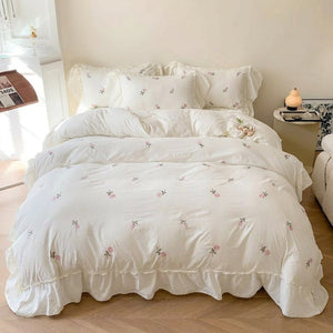 Parure de lit brodée de roses installée sur un grand lit dans une chambre chaleureuse