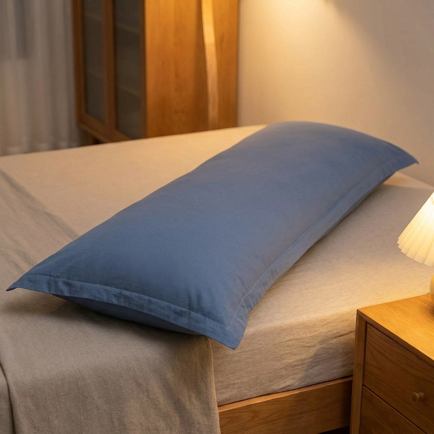 Taie de traversin bleu foncé installée sur un lit dans une chambre moderne avec table de chevet