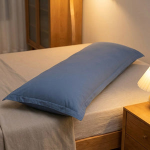 Taie de traversin bleu foncé installée sur un lit dans une chambre moderne avec table de chevet