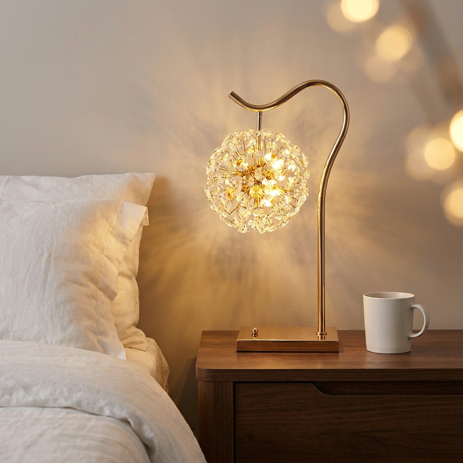 Lampe de table en cristal doré allumée sur une table de chevet dans une chambre élégante