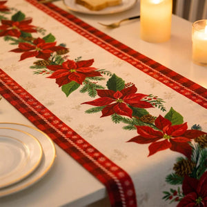 Gros plan sur le motif du chemin de table avec poinsettias rouges, pommes de pin et bordure à carreaux rouge et noir