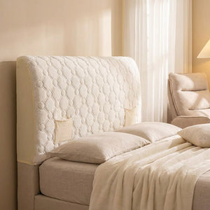 Housse de tête de lit matelassée ivoire dans une chambre lumineuse avec fauteuil