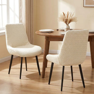 Deux chaises habillées de housses jacquard ivoire autour d'une table ronde en bois
