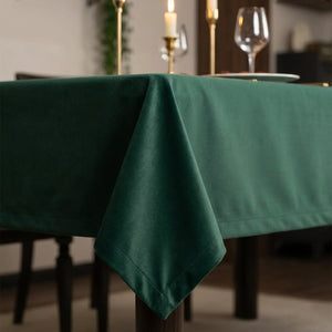 Gros plan sur le tissu vert chasseur effet cachemire de la nappe avec bougie et verre de vin en arrière-plan