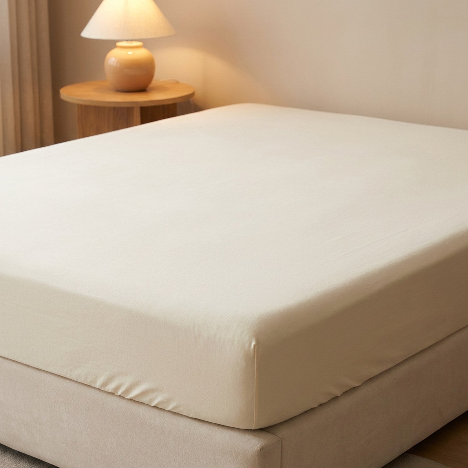 Drap housse beige sur un lit dans une chambre moderne avec table de chevet et lampe