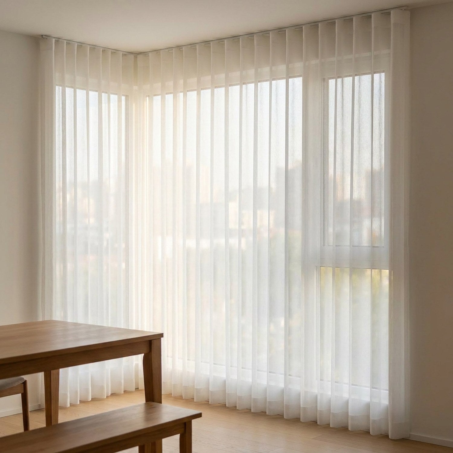 Rideau voile blanc habillant une baie vitrée d'angle dans une salle à manger lumineuse
