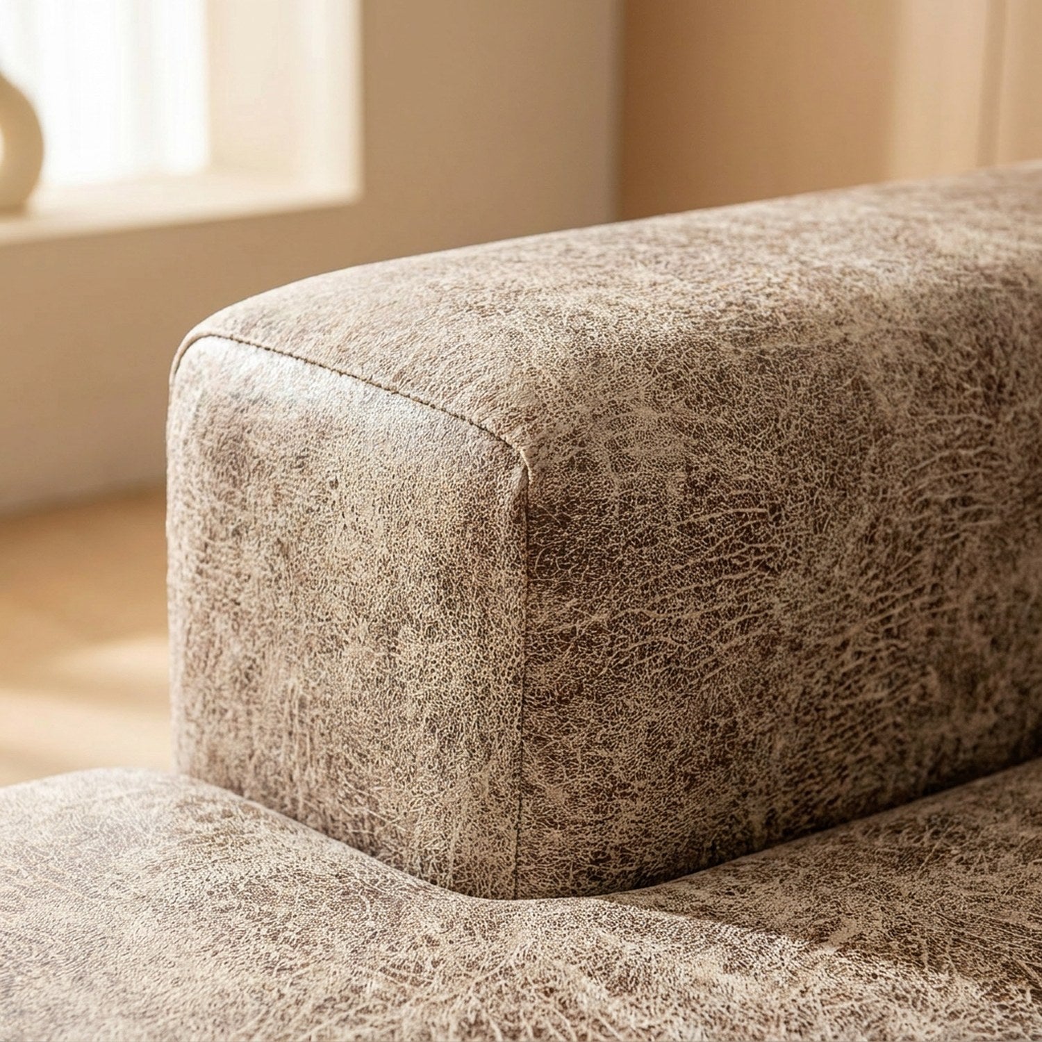 Gros plan sur l'angle d'un coussin recouvert par la housse beige taupe effet cuir