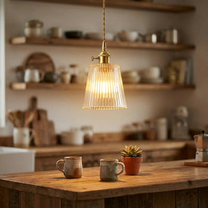 Suspension en verre strié laiton vintage allumée au-dessus d'un îlot de cuisine en bois, atmosphère chaleureuse