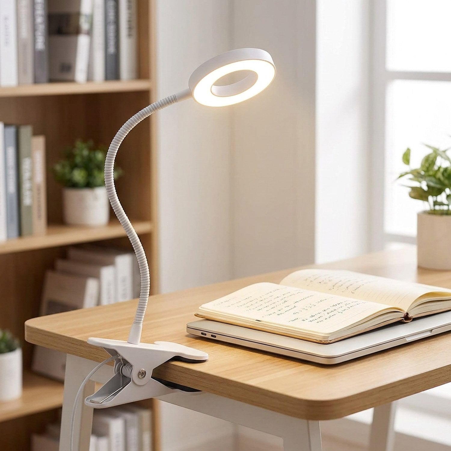 Lampe de bureau à pince éclairant un carnet et un ordinateur portable sur un bureau