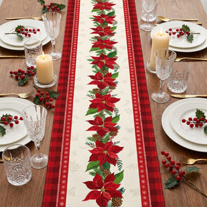 Vue plongeante du chemin de table de Noël déroulé au centre d'une table dressée avec vaisselle blanche et verres