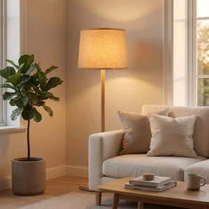Abat-jour tambour lin beige sur lampadaire dans salon scandinave avec plante verte