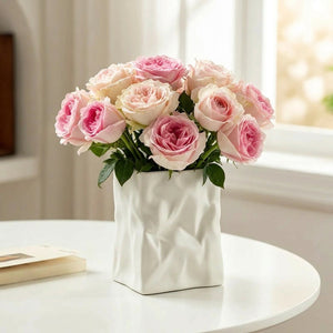 Vase résine froissée blanc avec roses roses sur table ronde blanche près d'une fenêtre