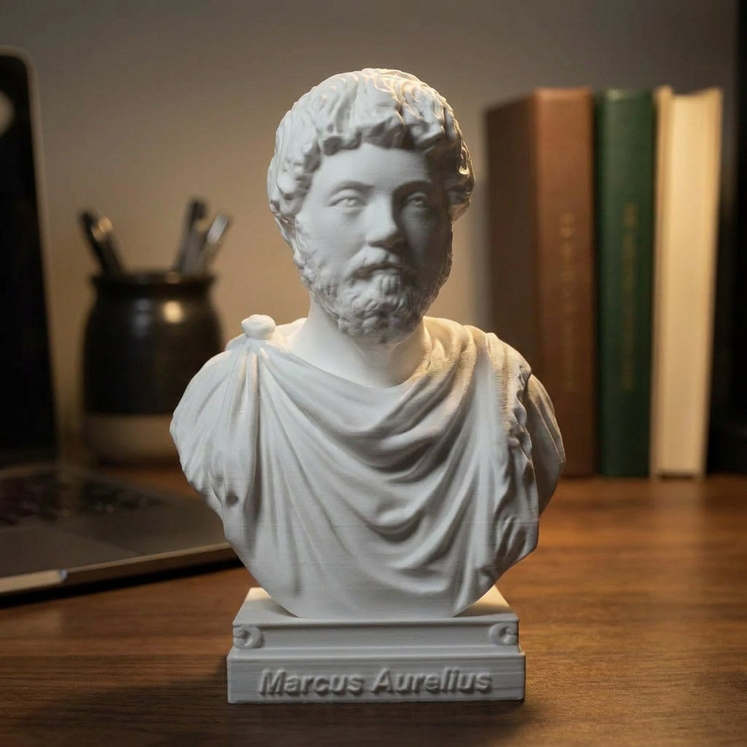 Buste de Marc Aurèle sur un bureau en bois sombre éclairé par une lampe chaude avec des livres en arrière-plan
