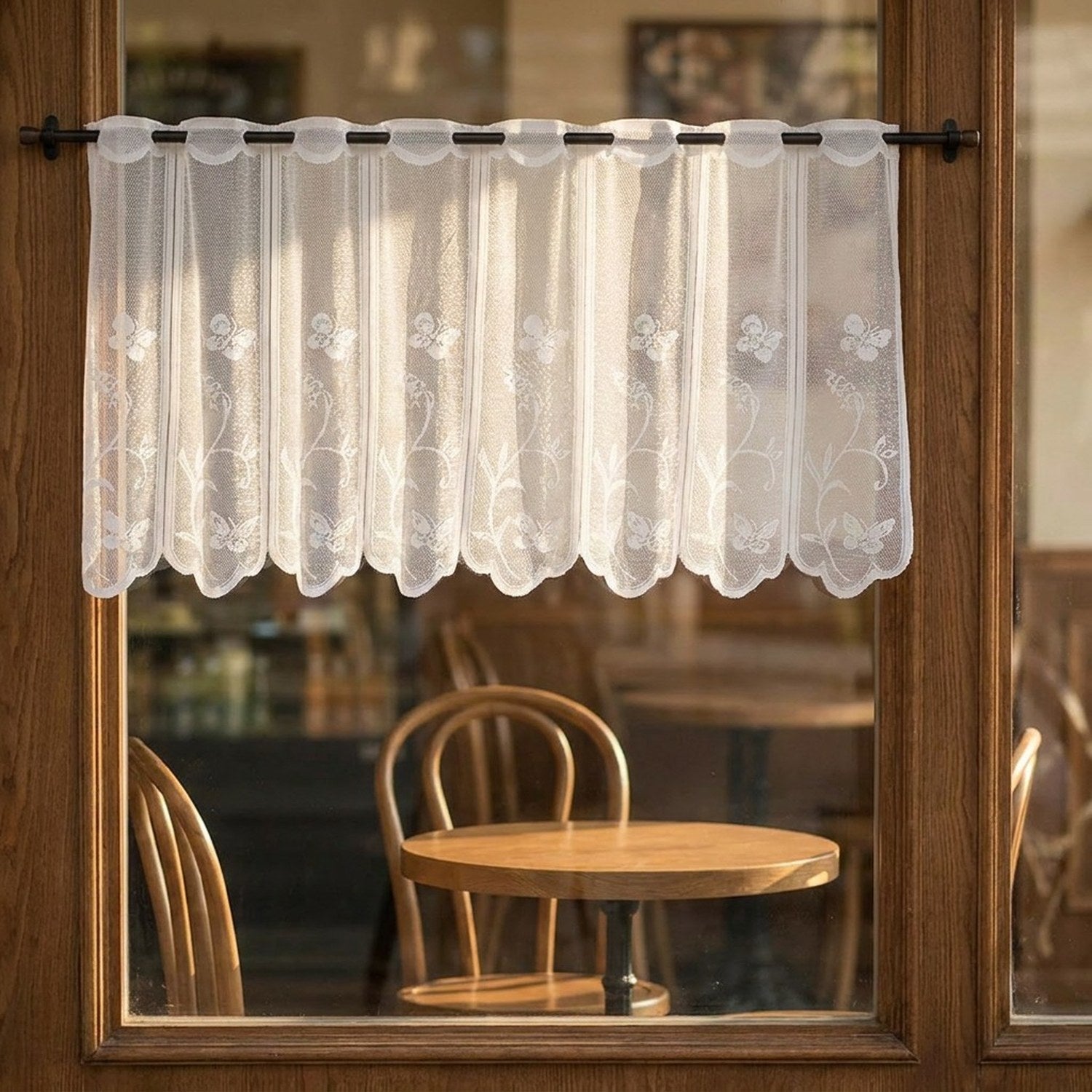 Brise bise en dentelle blanche accroché à la vitre d'un café avec table et chaises en bois