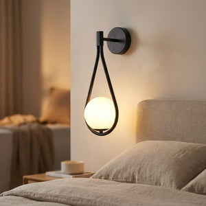 Applique murale noire installée au dessus d'une tête de lit en tissu beige