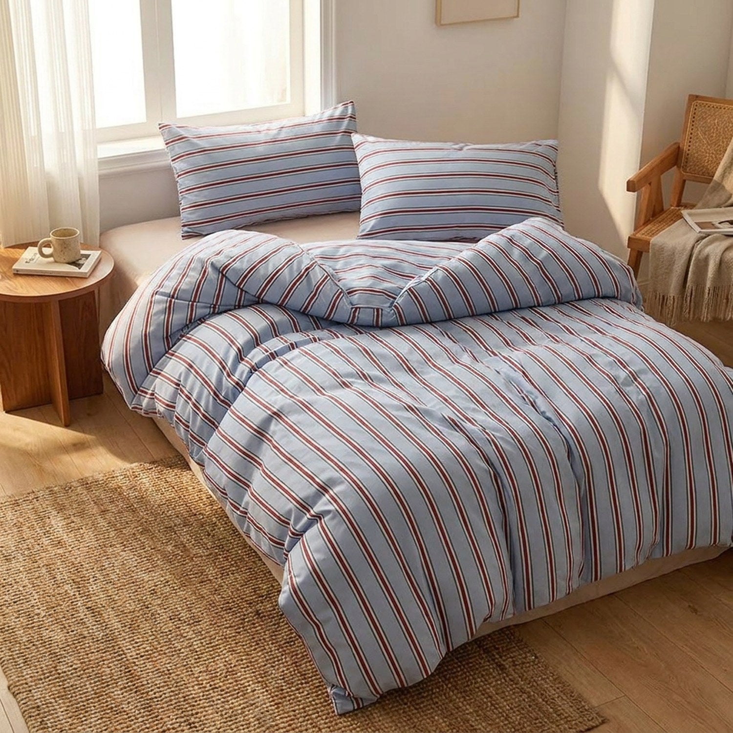 Parure de lit rayée bleue installée dans une chambre ensoleillée avec tapis en fibre naturelle