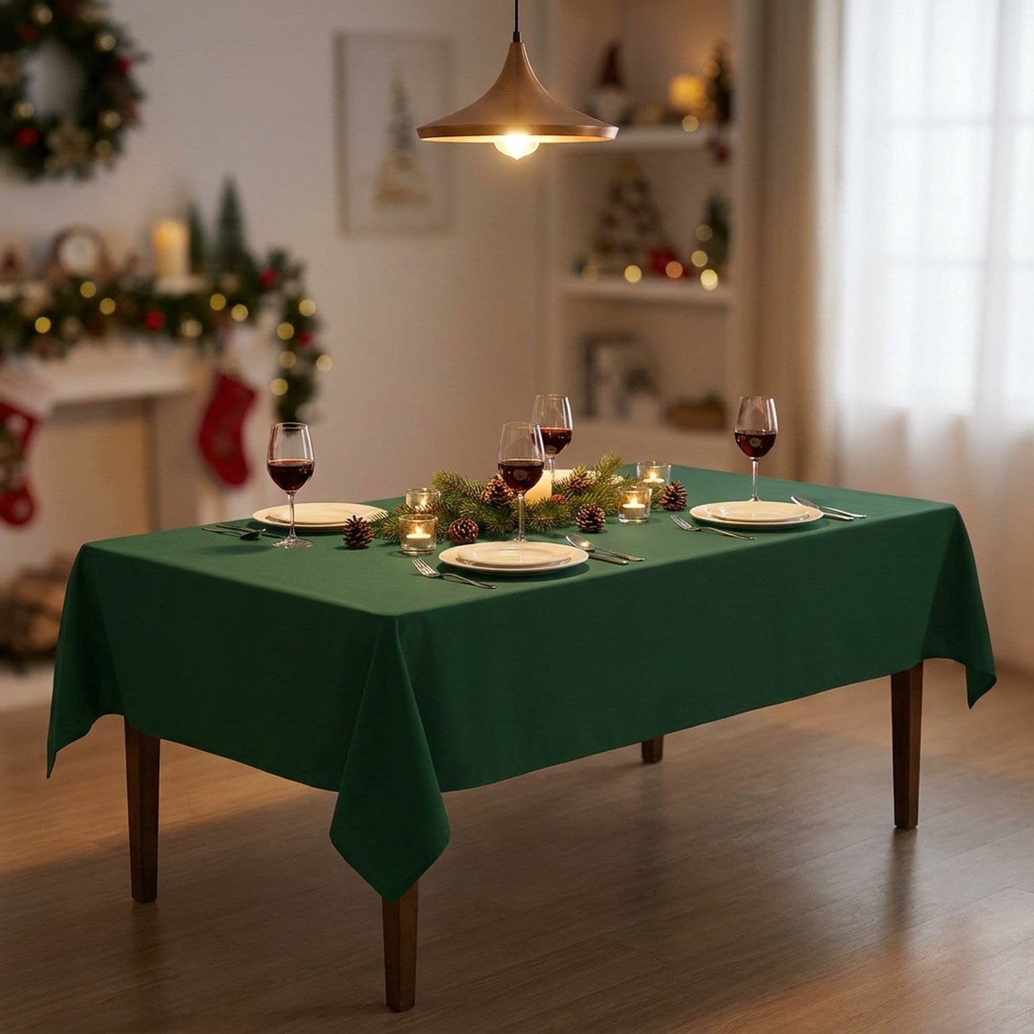 Table de repas de Noël pour quatre couverte de la nappe vert chasseur avec sapin illuminé en fond