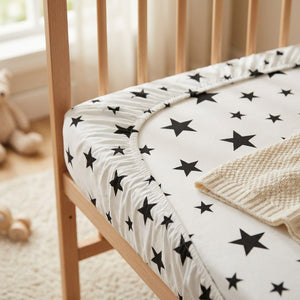 Détail du coin élastique du drap housse bébé motif étoiles sur le matelas de berceau