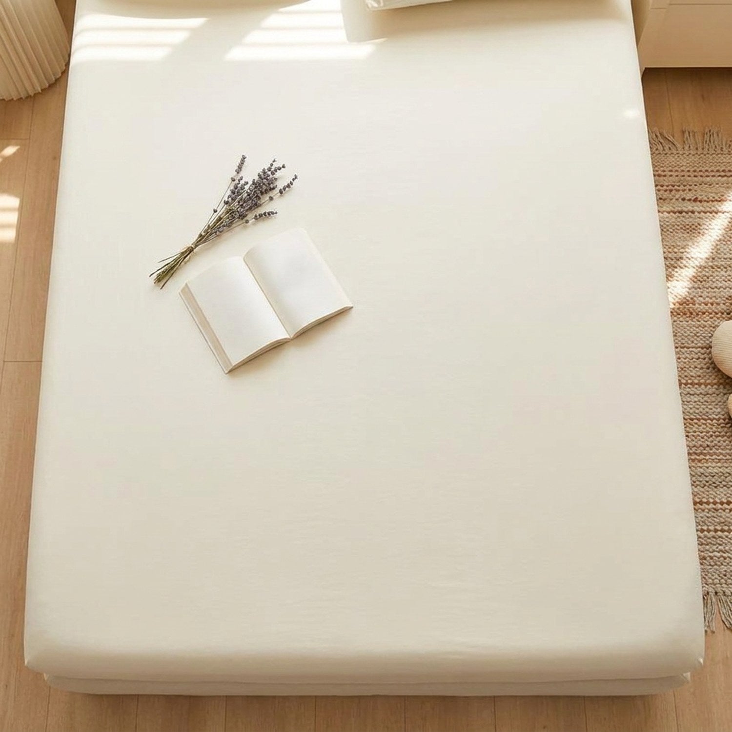 Vue du dessus d'un drap housse beige tendu avec un livre ouvert et des fleurs séchées