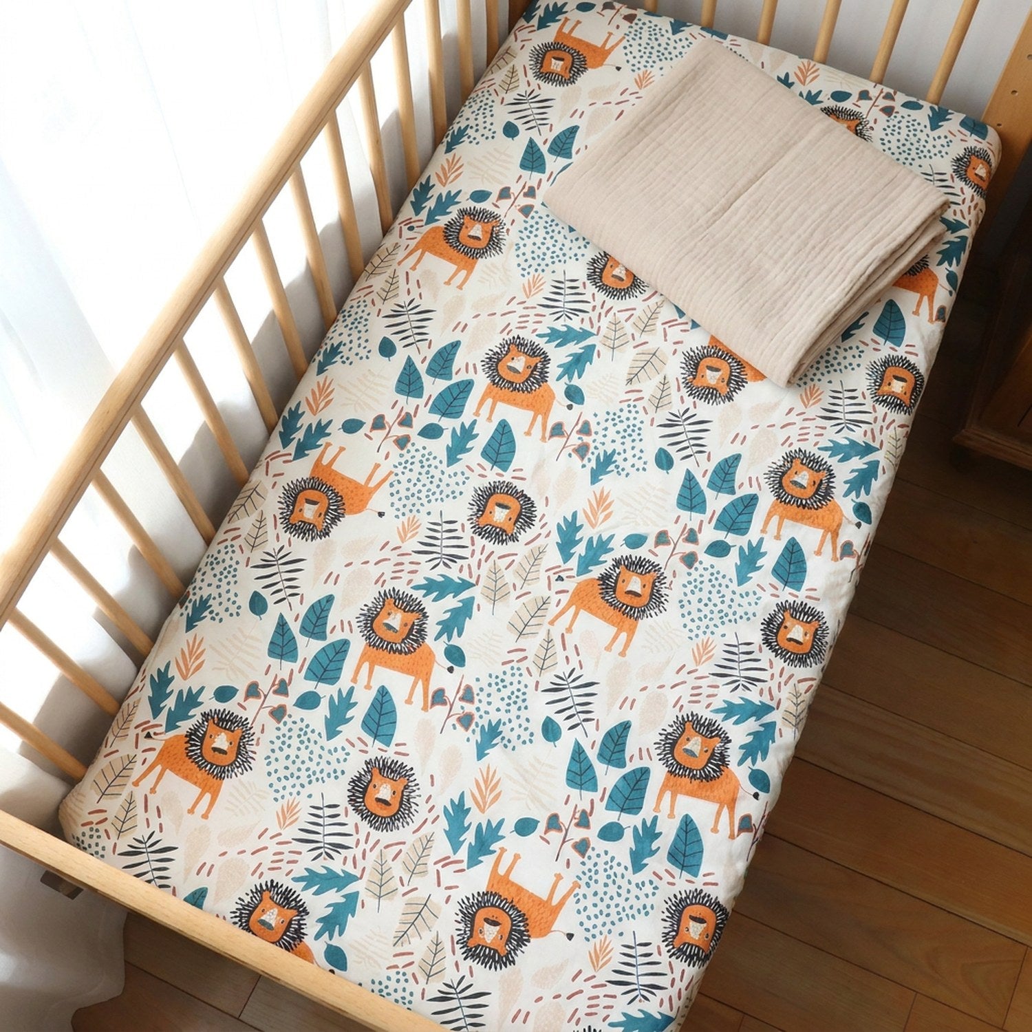 Vue de dessus du drap housse bébé motif lionceaux avec langue en mousseline pliée