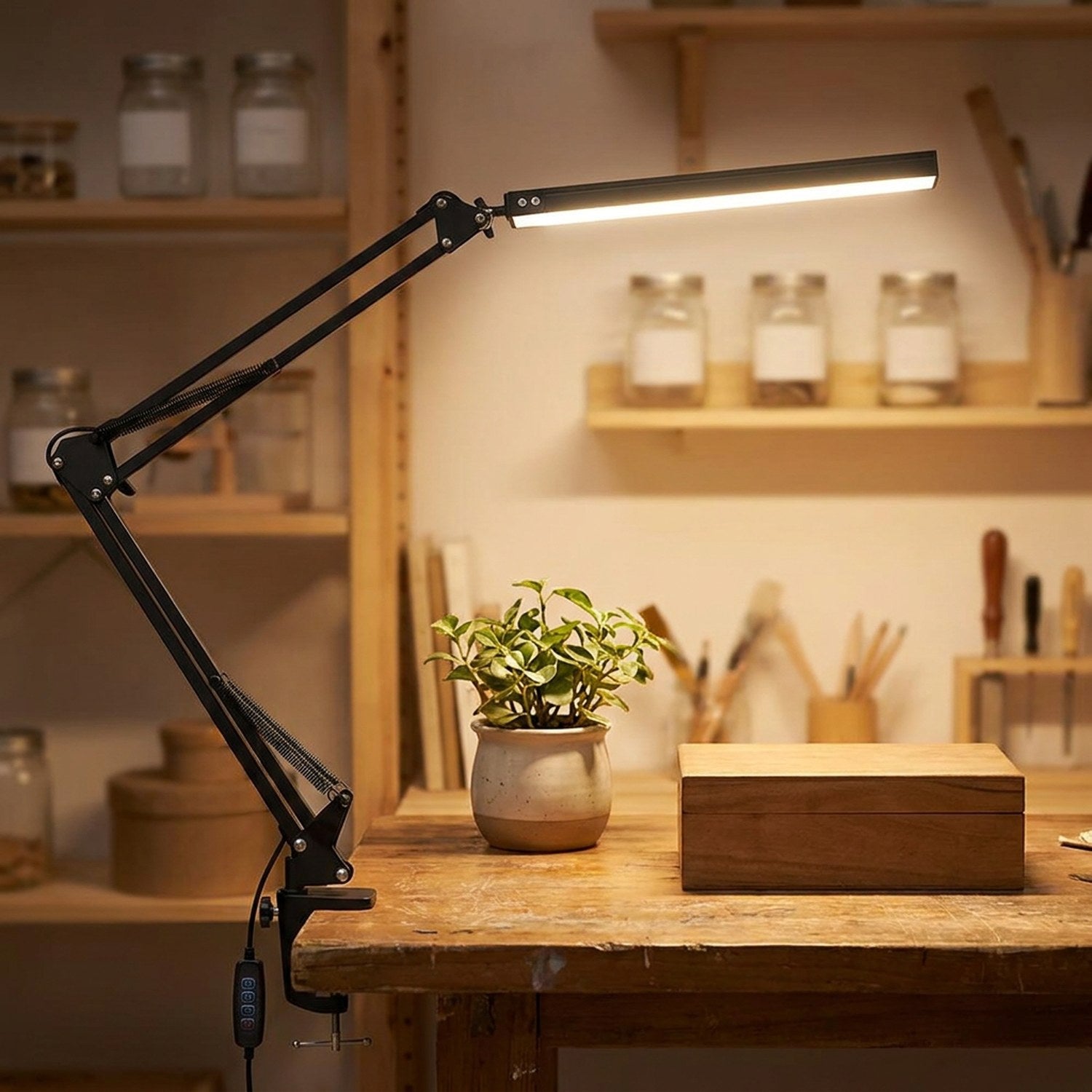 Lampe de bureau architecte noire clampée sur un établi en bois