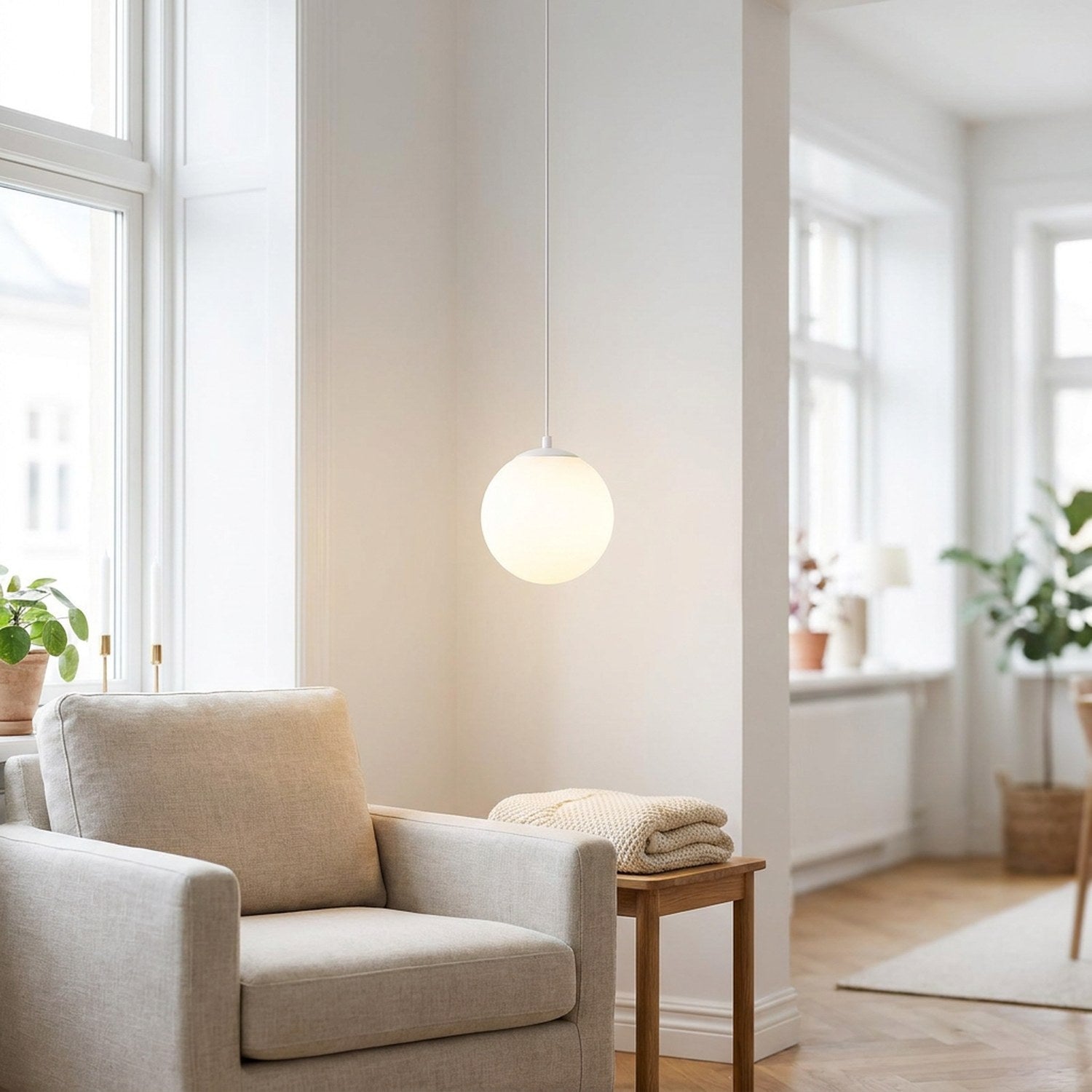Suspension boule en verre opalin blanche dans un salon scandinave lumineux