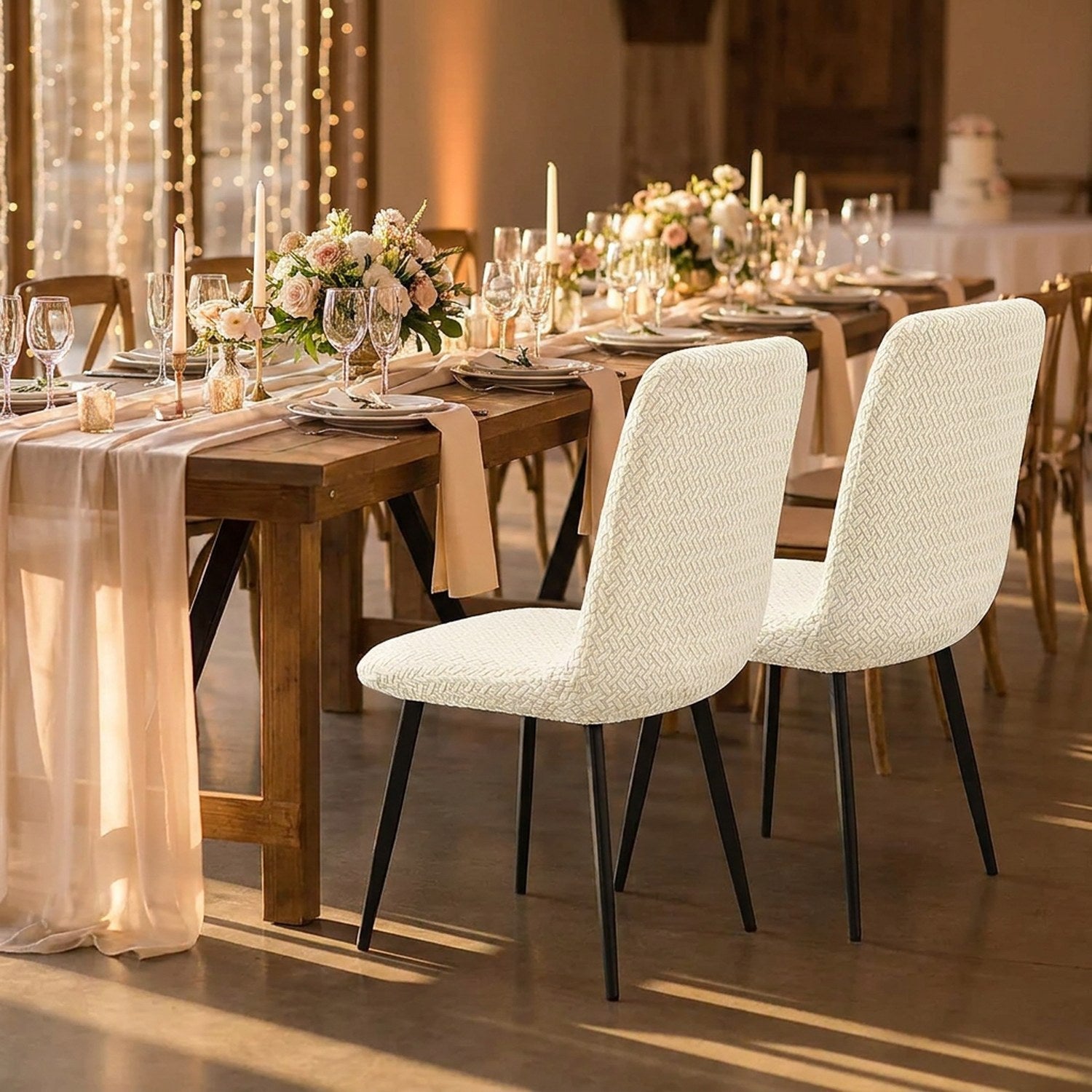 Chaises avec housses jacquard ivoire alignées le long d'une table de réception