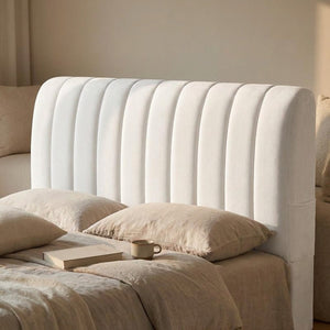 Housse de tête de lit blanche avec livre et tasse posés sur le lit en fin de journée
