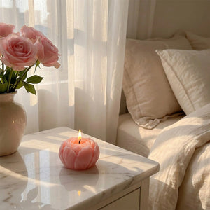 Bougie pivoine rose allumée sur table de nuit marbre dans chambre romantique