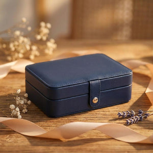 Boîte à bijoux en cuir bleu foncé présentée comme cadeau avec ruban et fleurs séchées