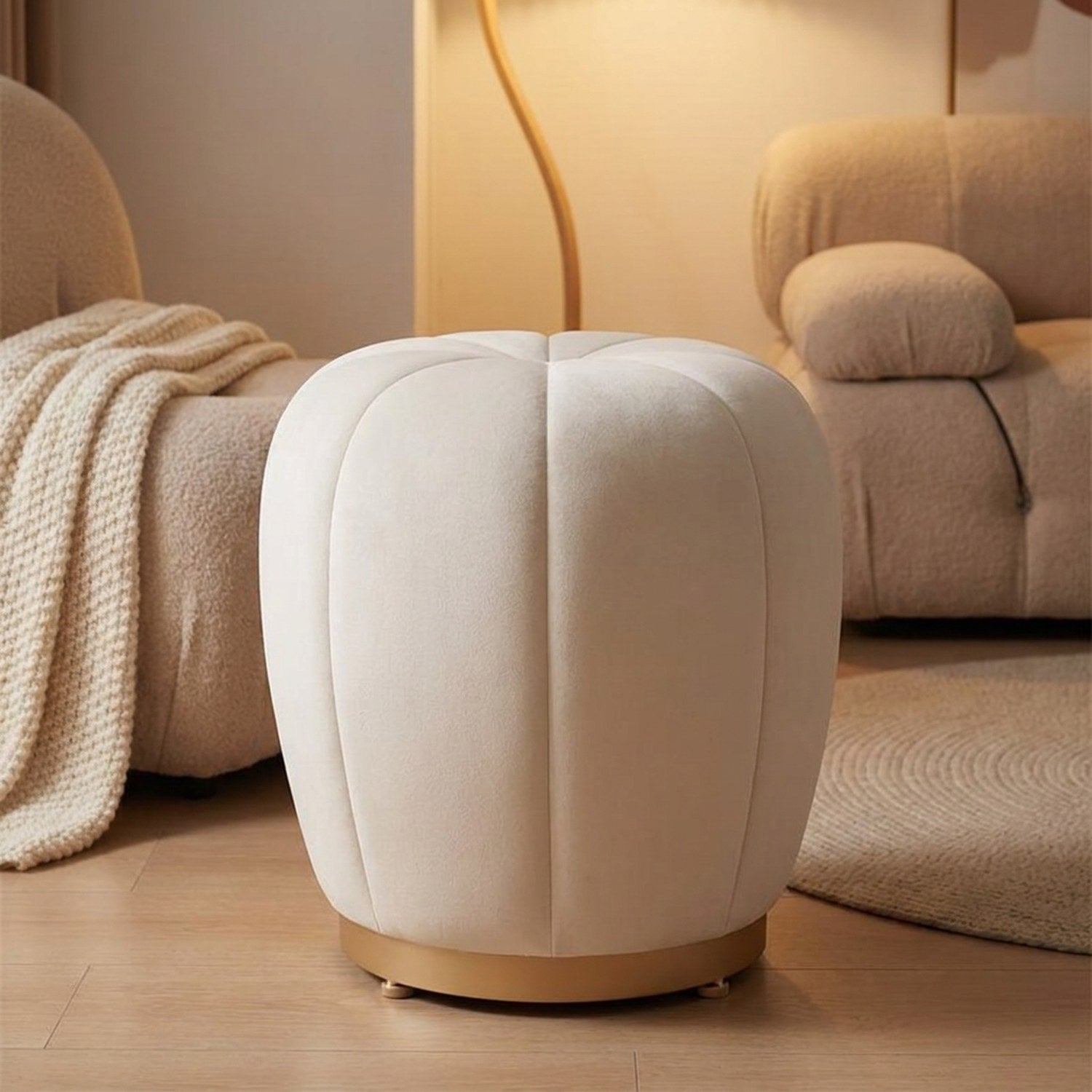 Pouf tabouret citrouille crème utilisé comme repose-pieds devant un fauteuil