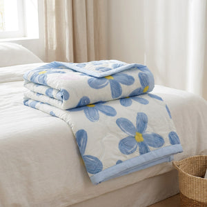 Couverture d'été à motif floral bleu pliée au pied d'un lit