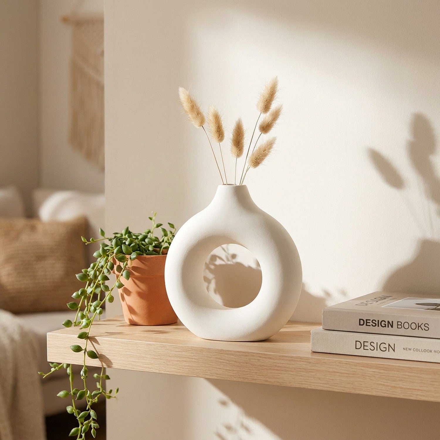 Vase anneau blanc sur une étagère en bois avec une plante retombante et des livres déco